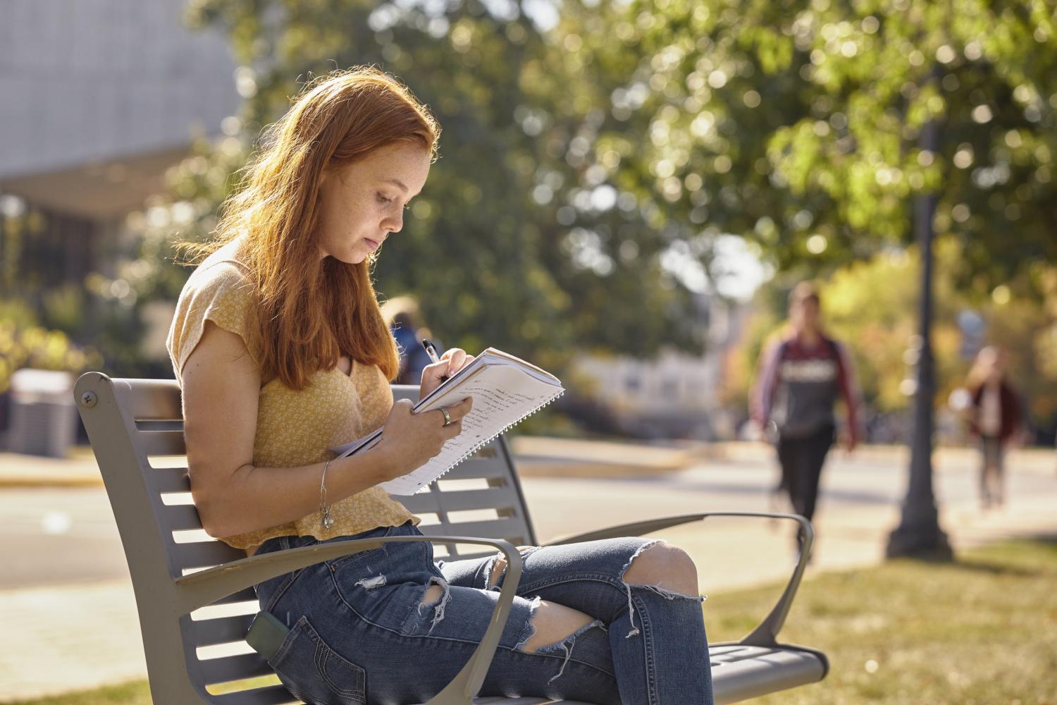 一位<a href='http://zsry.abe-men.com/'>全球十大赌钱排行app</a>学院的学生在校园里的长椅上读书.